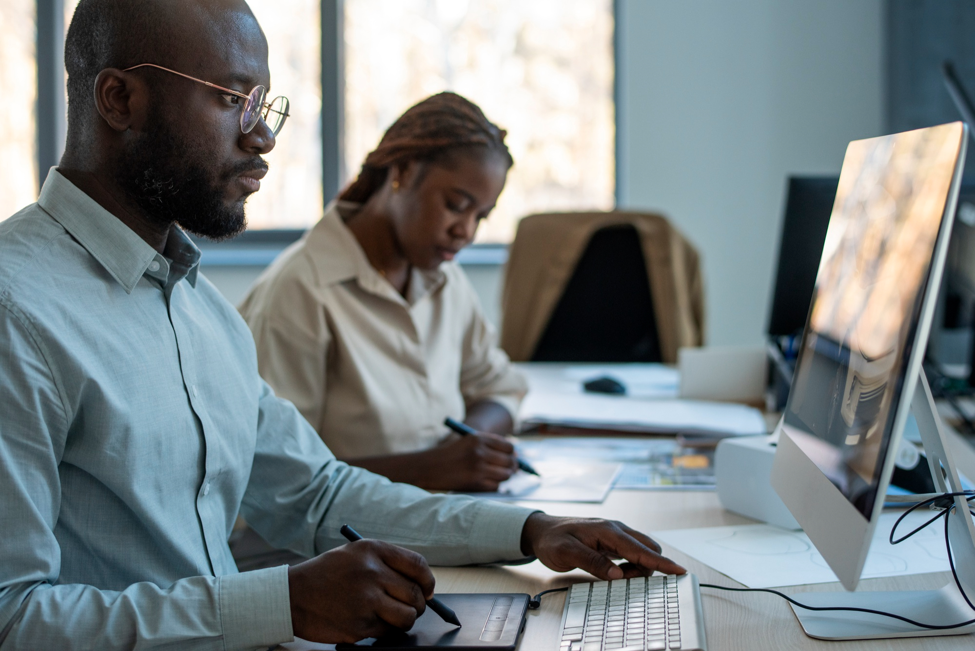 A focused male and female consultant working on the desktop.